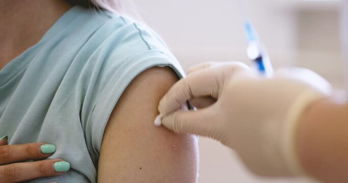 Medical Clinic Closeup Vaccination Against Covid-19 Vaccination Cabinet Vaccine Medicine Health care Hospital Doctor Nurse Hand Syringe Ampoule Needle Sterile Shoulder Patient Slow motion Pandemic - Powered by Adobe