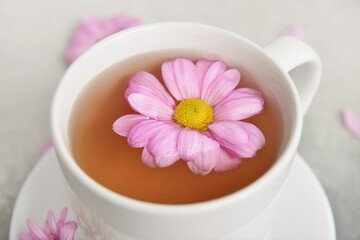 Fototapeta na wymiar Cup of floral tea with flower on light background, closeup