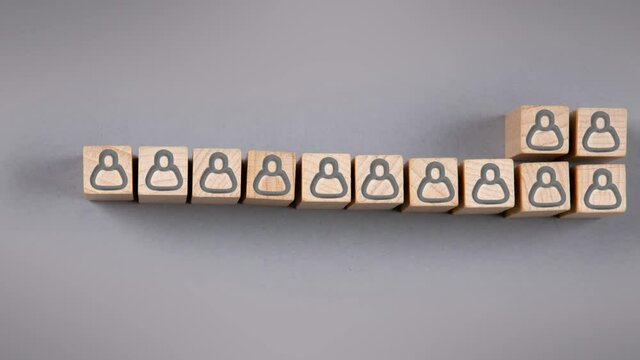 Wooden blocks with black human icons being gathered in a row on gray background. Leadership, HR and Teamwork Concept. Gray background. High quality 4k video