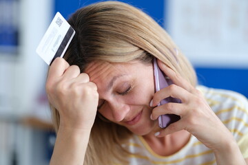Upset woman talking on phone and holding plastic bank card