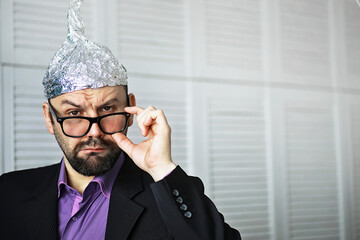 Bearded funny man in a cap of aluminum foil. Concept art phobias.Conspiracy theory. Conspiracy....