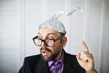 Bearded funny man in a cap of aluminum foil. Concept art phobias.Conspiracy theory. Conspiracy....