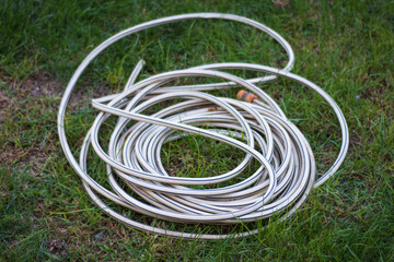 rolled up plastic garden irrigation hose on the grass.
