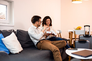 Smiling couple sitting on sofa and eating fast food salad at home.