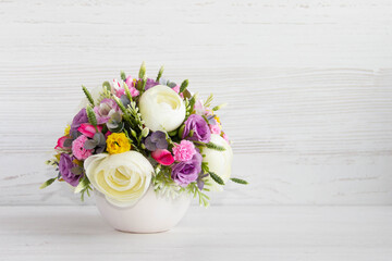 beautiful flowers in a white vase on a wooden background.