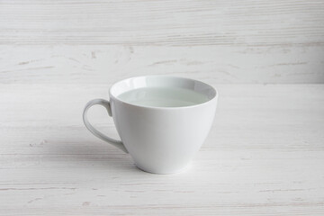transparent clean water in a white cup on a wooden background
