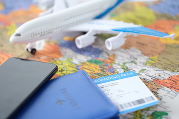 Smartphone and passport with tickets lie on world map with small plane