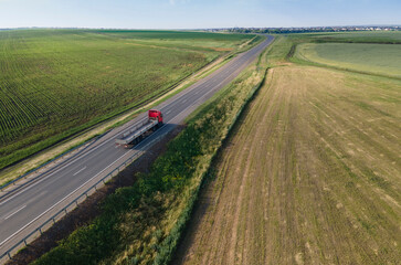 Red tipper truck on street road highway transportation. Semi-truck countryside aerial view.