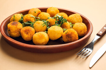 Naklejka na ściany i meble Plate with fried potato balls on color background