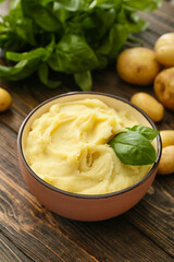 Bowl with tasty mashed potatoes on wooden background