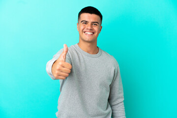Young handsome man over isolated blue background with thumbs up because something good has happened