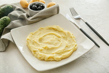 Plate with tasty mashed potatoes on light background