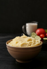 Bowl with tasty mashed potatoes on dark wooden background