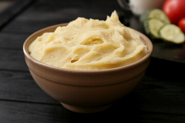 Bowl with tasty mashed potatoes on dark wooden background