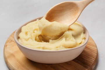 Bowl with tasty mashed potatoes on light background, closeup