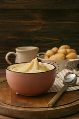 Bowl with tasty mashed potatoes on wooden background