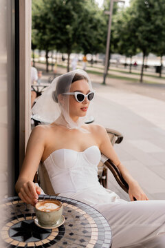 French fashion woman look in white suit. Brunette woman in cafe, woman outdoor portrait