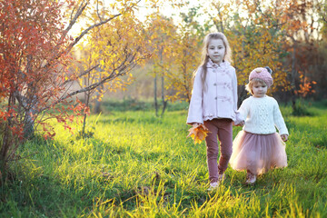 Young family on a walk in the autumn park on a sunny day. Happiness to be together.