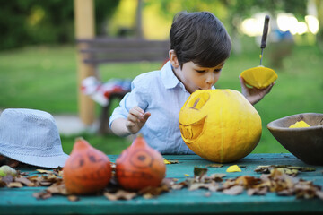 Fototapeta premium Autumn traditions and preparations for the holiday Halloween. A house in nature, a lamp made of pumpkins is cutting out at the table.