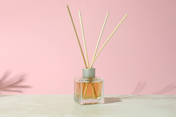 Diffuser bottle with sticks against pink background