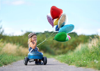 Kind im Tretauto mit Ballons