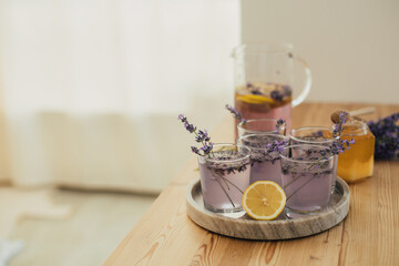 Fresh lavender lemonade and jar with honey on a kitchen table.