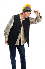 a worker in a yellow protective helmet and a black vest looks into the distance. put his hand to his forehead. isolated white background