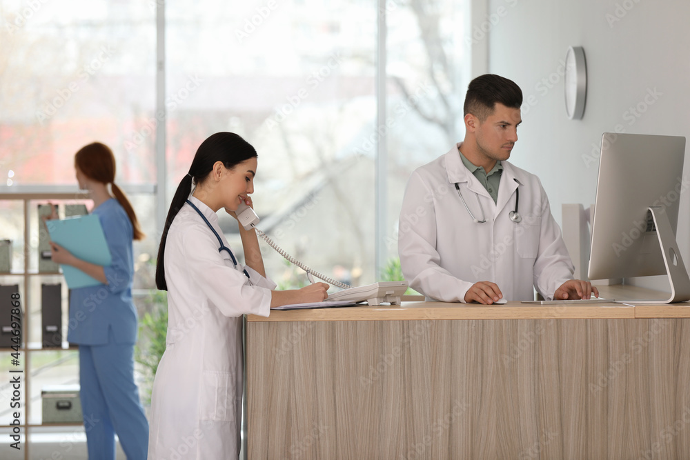 Wall mural receptionist and doctor working at countertop in hospital