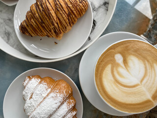Two delicious croissants and a cup of invigorating cappuccino on the table close-up