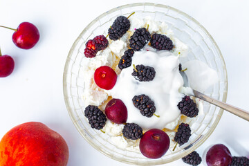 Summer food. A bowl with cottage cheese and ripe juicy cherries and mulberries, coconut cream. A healthy tasty dessert