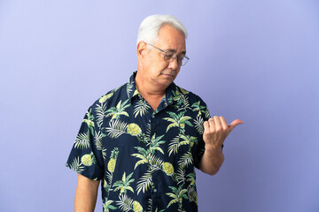 Middle age Brazilian man isolated on purple background unhappy and pointing to the side