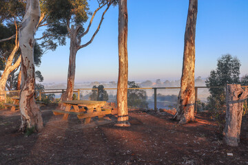 picnic benches in misty morning landscape with view