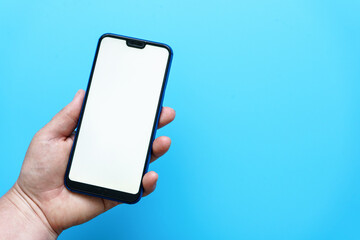 Weibliche Hand hält ein Smartphone mit einem weißen leeren Display. Blauer Hintergrund.