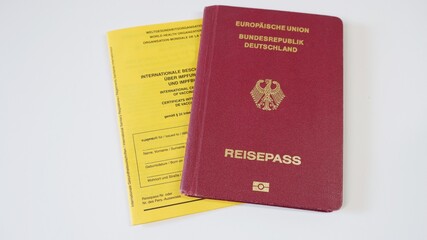 A German European passport and a yellow WHO vaccination certificate lie on a white background