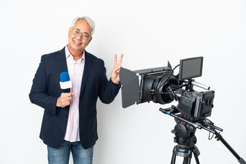 Reporter Middle age Brazilian man holding a microphone and reporting news isolated on white background smiling and showing victory sign
