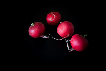 A blue wicker basket with bright red fresh radishes with green leaves stands on a blue wooden table. Close-up.
