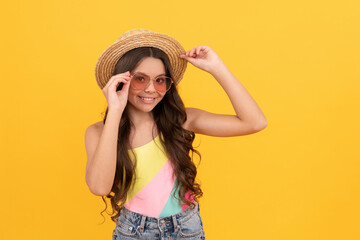 happy kid in summer straw hat and glasses has curly hair on yellow background, summer fun