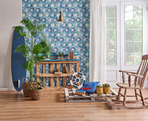 Modern living room, blue wallpaper, decorative wooden palette bookshelf, surfboard style,wood rocking chair, gold lamp vase of green plant and home accessory.