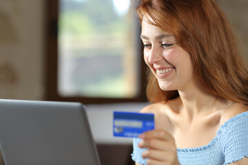 Happy woman using laptop paying with credit card