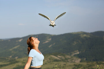 Woman breathing fresh air in nature and a owl flying above