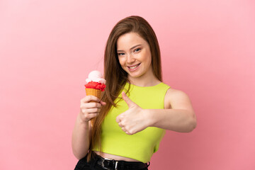 Teenager girl with a cornet ice cream over isolated pink background with thumbs up because something good has happened