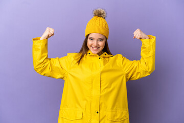 Teenager girl wearing a rainproof coat over isolated purple background doing strong gesture