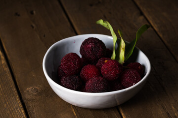 a bowl of bayberry fruit on a wooden plank