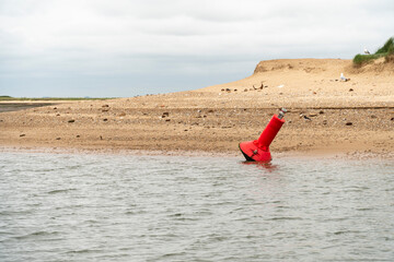 Red navigational buoy at low tide