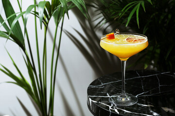 citrus cocktail close up on marble table and tropic plants on background. maandrin or tangerine cocktail. summer fresh drinks