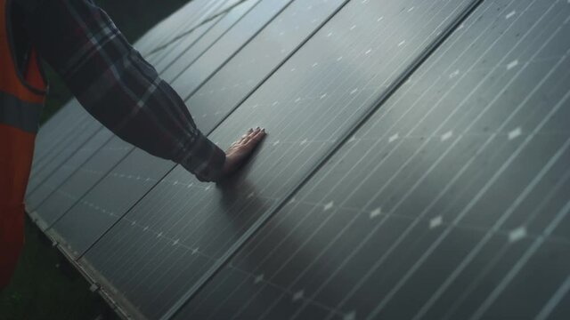 Girl engineer touches with a gloved hand photovoltaic electric solar panel battery. Checks the installation and efficiency of renewable energy. Fingers cleans the dirt. Energy Innovation Park.