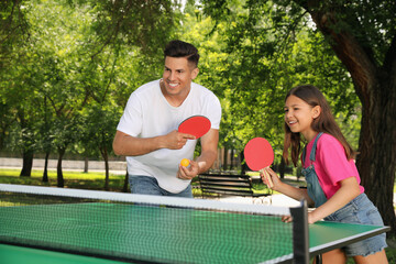 Happy man with his daughter playing ping pong in park - obrazy, fototapety, plakaty