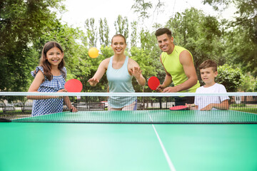 Happy family playing ping pong in park