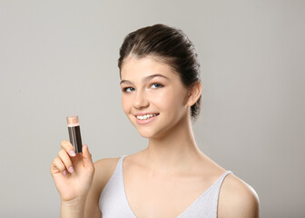 Beautiful girl with stick foundation on light grey background