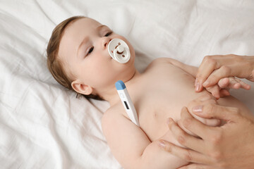 Mother measuring her baby's temperature, closeup. Health care
